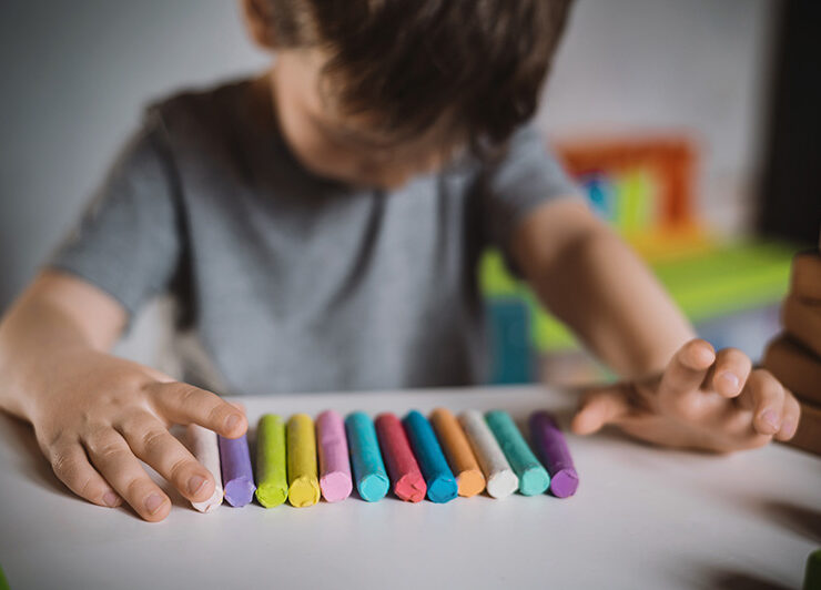 Un niño con autismo mira hacia abajo mientras juega con arcilla durante una sesión de terapia.